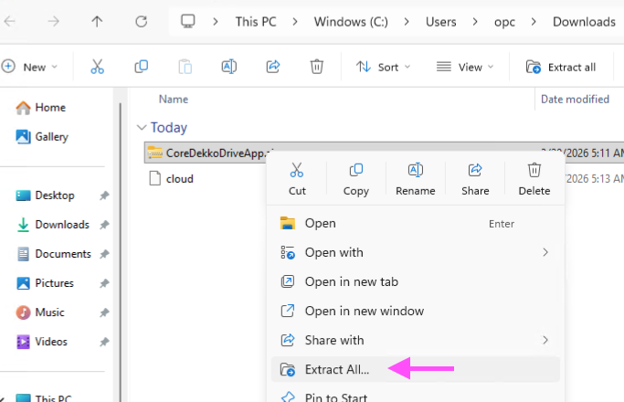 Windows File Explorer context menu open on CoreDekkoDriveApp.zip in Downloads, with the "Extract All..." option highlighted by a pink arrow.